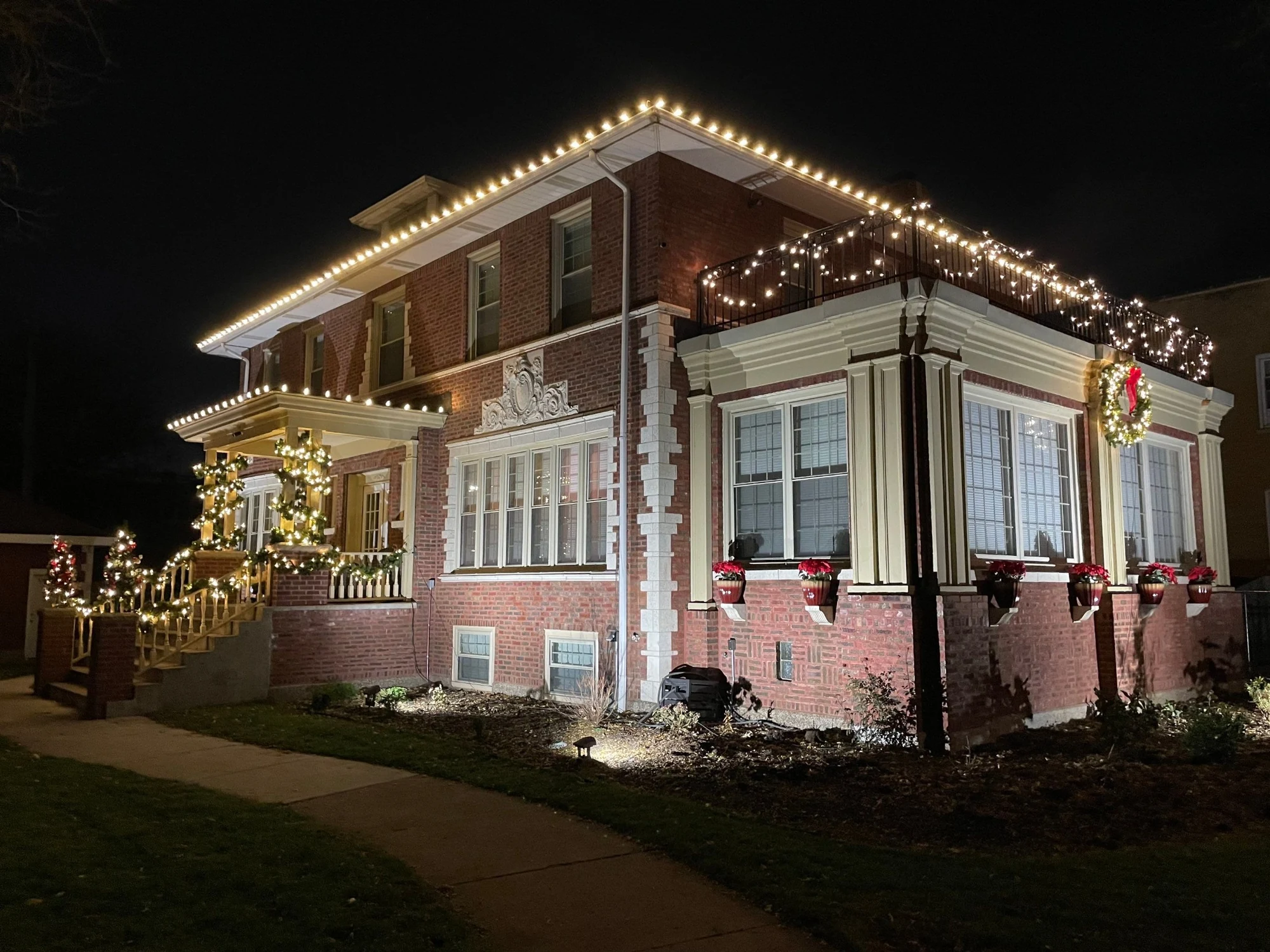 Warm holiday roofline lighting following the peaked rooflines of a brick home